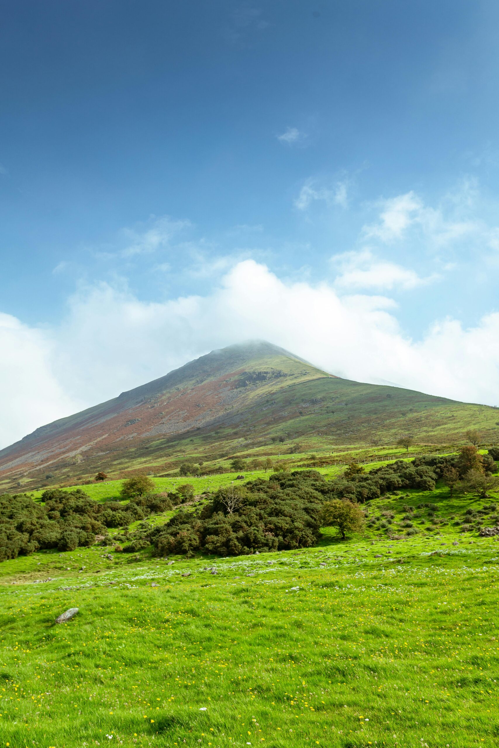 Breathtaking view of a hill in Wasdale Head, showcasing lush green fields under a blue sky.